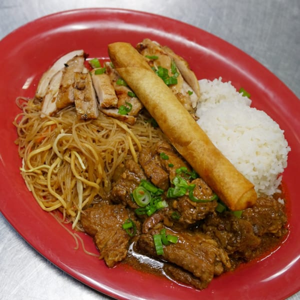 Filipino plate with chicken adobo, beef caldereta, pancit, rice, and a lumpia on a red plate.